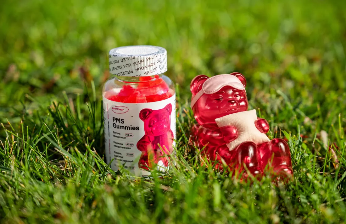 Банка PMS Gummies на траве и розовый мармеладный мишка с подушкой